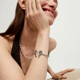Pulsera rígida abierta de aleación de metales bañada en plata, con detalle de alas en los extremos.