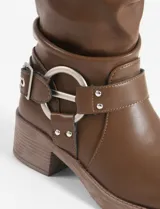 Botas marrones de caña media con hebillas plateadas y taco bajo. Fabricadas en cuero vegano.