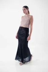 Vestido largo de fiesta con cuello halter y lentejuelas color verde esmeralda en el top y negro en la falda.