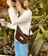 Riñonera de gamuza color chocolate con cierre azul marino y correa ajustable.