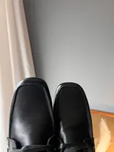 Mocasines de cuero negro con cordones finos y suela plana.