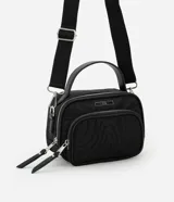 Bandolera negra de formato rectangular con textura capitoneada, correa ajustable, bolsillo externo y cierre de cremallera.