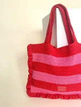 Bolso tipo tote tejido a crochet, con hilo 100% algodón, a rayas horizontales color crema y lila, con volados en los bordes y manijas reforzadas.