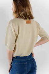 Sweater color dorado de tejido de punto suave con hilos metalizados, corte recto y mangas cortas con puño ajustado.