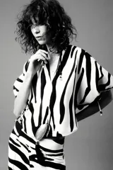 Top de cuello redondo y escote pico con estampado animal print cebra en blanco y negro. Manga corta abullonada ajustable con lazadas.