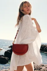 Bolso bandolera rígido color rojo, con asa corta y correa larga de tejido tipo canvas. Cierre con solapa e imán y bolsillo interior con cremallera.