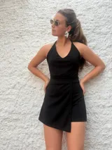 Mono corto negro con escote halter y falda cruzada.