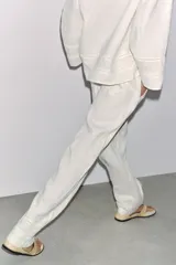 Pantalón blanco de lino con tiro medio, cintura ajustable con cordones, bolsillos laterales ocultos y detalle de entredós combinados a tono.