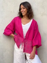 Blusa marrón de lino con escote en V, mangas largas abullonadas y detalle de encaje en la parte inferior.