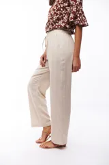 Pantalón de viscosa y lino color beige, de corte recto, con cintura elástica y cordón ajustable.