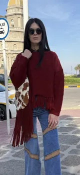 Sweater tejido en lana color borgoña, con cuello redondo y terminación con flecos.