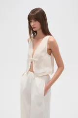 Chaleco color crudo sin mangas con escote en V y lazo de ajuste en el frente.