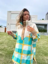 Buzo largo con cuello alto de polar color crema y cuerpo con estampado de cuadros en tonos celeste, amarillo y blanco.
