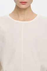 Camiseta blanca de manga corta con cuello redondo, corte holgado y apliques de pequeñas perlas en la parte delantera.