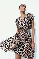 Vestido corto sin mangas en tejido fresco de algodón con estampado animal print. Modelo con escote cruzado en V, pliegues en los hombros, cintura fruncida y pollera con vuelo.
