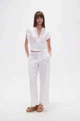 Top blanco de manga corta con escote en V, detalles bordados de hojas y puntos, pinzas, punto smock en la cintura y volados en los hombros.