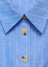 Vestido midi de algodón y lino, color celeste con rayas verticales blancas. Presenta cuello camisero, diseño sin mangas con tirantes anchos, cierre de botones frontales, cinturón con hebilla y falda evasé.