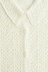 Camisa color crema de tejido crochet con cuello clásico, cierre frontal con botones y mangas cortas.