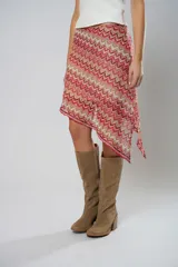 Minifalda roja con estampado de ondas en tonos rosados y beige, con corte irregular y cinturón marrón.