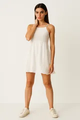 Vestido corto blanco de bretel fino, con cuerpo superior de punto crochet, falda evasé y cuello recto.