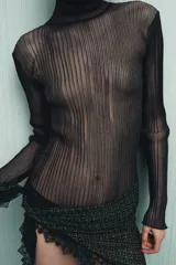 Pañuelo tipo pareo estampado con un patrón geométrico en tonos verde, naranja y negro. Presenta un borde de encaje negro a contraste.