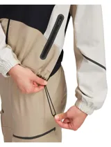 Campera deportiva negra, beige y blanca con cierre frontal, cuello alto y cintura ajustable con cordón.