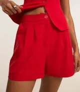 Short de vestir color marrón chocolate, de tiro alto, con pliegues delanteros, trabillas en la cintura, bolsillos laterales tipo cuchillo y bolsillos embutidos en la parte trasera.