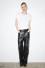 Pantalón de cuero negro, de tiro medio, con trabillas en la cintura, cinco bolsillos, pespuntes marcados a tono, pierna recta y cierre frontal con cremallera y botón.