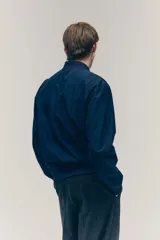 Campera bomber azul marino con cuello elevado acanalado y cierre frontal. Tiene bolsillos laterales y un bolsillo interior, todos con cierre. Los puños y el bajo son acanalados. Está forrada.