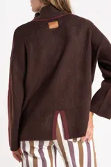 Sweater negro de tejido grueso con cuello alto acanalado. Presenta una franja decorativa en las mangas y el cuello en hilo marrón con brillo (lurex).