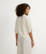 Blusa color crema con estampado animal print de jaguar en tonos dorados, escote en V, mangas 3/4 y nudo en la parte inferior.