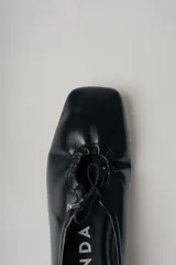 Ballerinas negras de cuero con punta redondeada y detalle de lazo ajustable.