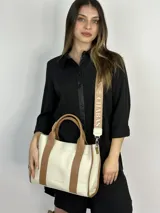 Bolso tote color crema con detalles en cuero marrón. Tiene doble asa de mano y correa de hombro extraíble con el logo de la marca.
