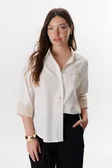 Camisa verde militar de manga larga con puños color crema, cuello clásico y cierre frontal con botones. Tiene un bolsillo en el pecho con bordado de una palmera color crema.