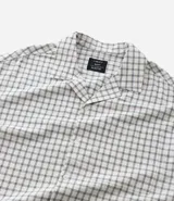 Camisa de hombre de manga corta, cuello inglés y corte boxy, confeccionada en algodón tricolina texturizada a cuadros. Presenta abotonado frontal y bordado en la espalda.