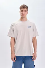 Camiseta manga corta oversize color gris claro con estampa azul en la espalda que incluye texto "Fizz & Tea" y el dibujo de un vaso con hielo.