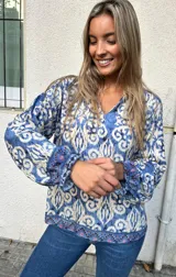 Blusa boho-chic de fondo azul y crudo, con cuello camisero y mangas ajustadas en los puños.