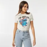 Camiseta blanca de corte crop fit con estampado de Stitch con la bandera de Estados Unidos y la frase 'Los Angeles California - USA'.