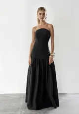 Vestido largo negro strapless con corte ajustado en el torso y falda amplia con frunce en la cintura. 