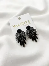 Par de aros colgantes con forma de hojas, con piedras facetadas negras y grises.