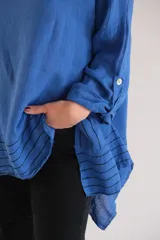 Blusa azul con mangas 3/4 y detalle de tiras horizontales negras en el ruedo.