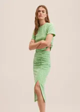 Falda midi de tiro alto con estampado a cuadros vichy en verde y blanco, con frunce lateral y abertura en el ruedo.