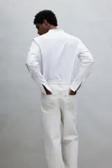 Camisa blanca de corte estándar, con cuello mao, tapeta clásica, canesú en la espalda, mangas largas con puños abotonados y bajo redondeado.