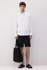 Camisa blanca de lino y algodón con cuello inglés, tapeta clásica y canesú en la espalda. Modelo de manga larga con bolsillo superior abierto, cierre ajustable de botón en los puños y tapeta con botón. Bajo redondeado. Corte estándar.