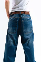 Pantalón de jean azul desgastado, corte mega baggy, con estampa serigrafiada en la pierna y botones personalizados.