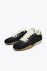 Zapatillas deportivas negras con detalle de estampado animal en la parte trasera, suela color caramelo y ajuste con cordones.