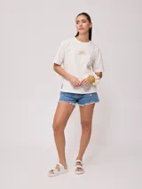 Remera color amarillo claro con estampado en el frente que incluye un sol y el texto 'Rusty Club'. Corte holgado.