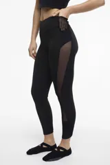 Calza deportiva larga negra con cintura alta, detalles de transparencias laterales en tul y bolsillos laterales.