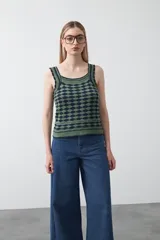 Top tejido sin mangas con diseño geométrico de rombos en relieve, en tonos azul marino y beige. Presenta escote amplio y breteles tejidos.