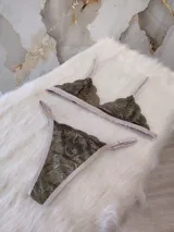 Conjunto de lencería de encaje verde musgo con detalles en beige, compuesto por un corpiño triangular sin aro y una tanga con tiras ajustables.